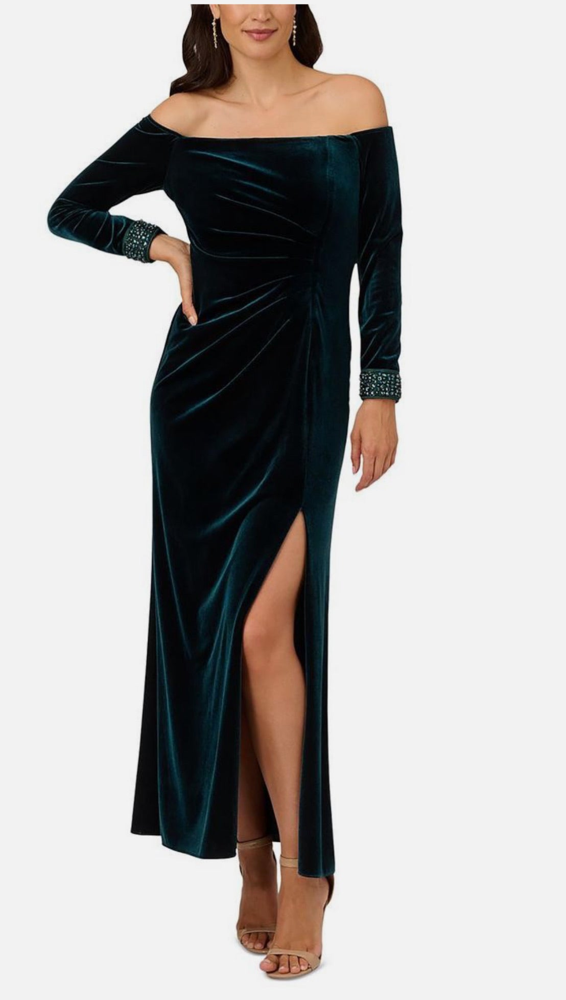 Woman wearing a teal velvet off-shoulder gown with long sleeves on a white background