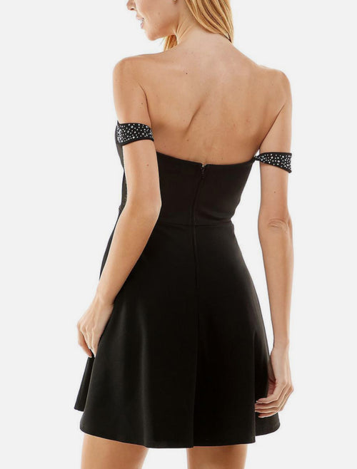 Black off-shoulder dress with sparkling details on a white background