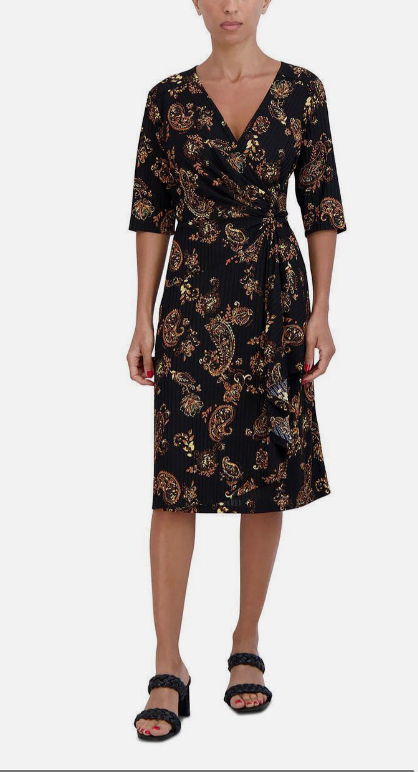 Woman wearing a black dress with gold floral pattern on a white background