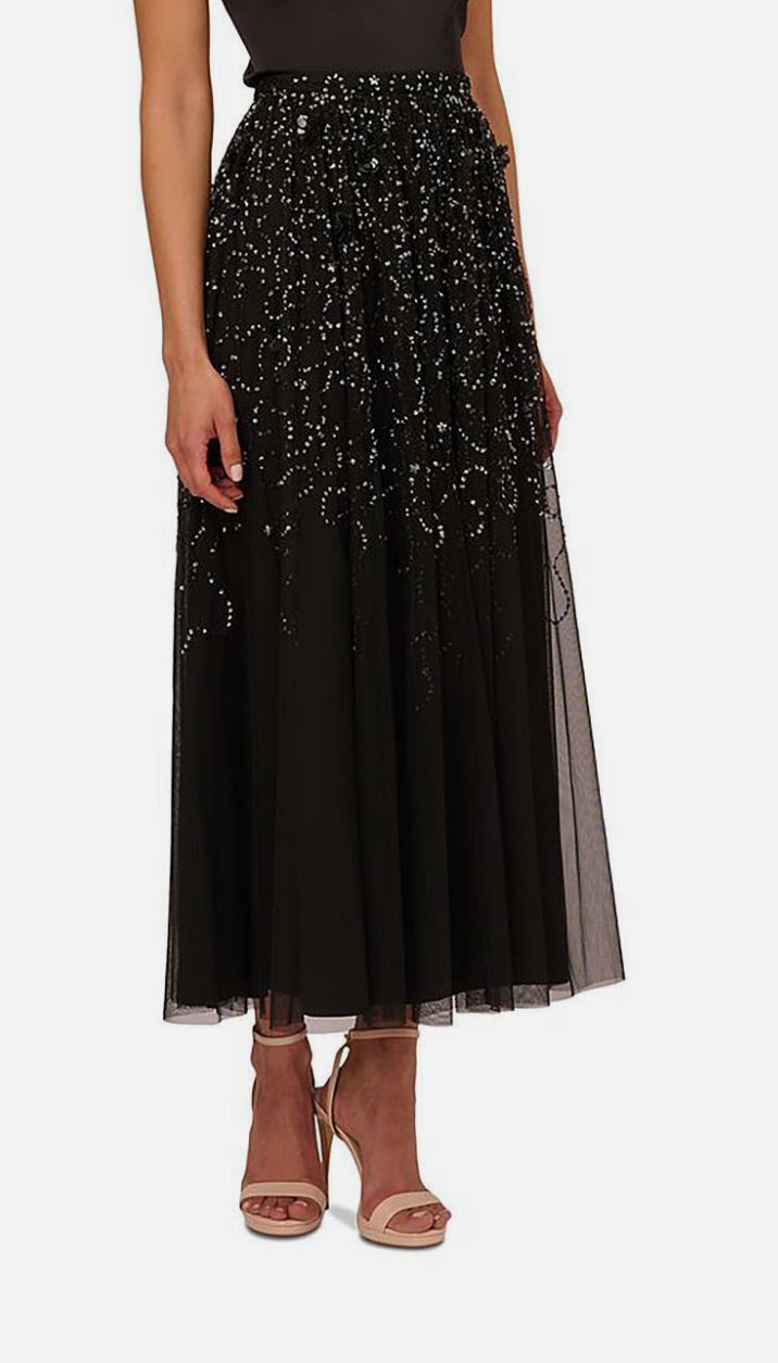 Black beaded skirt worn by a person on a white background